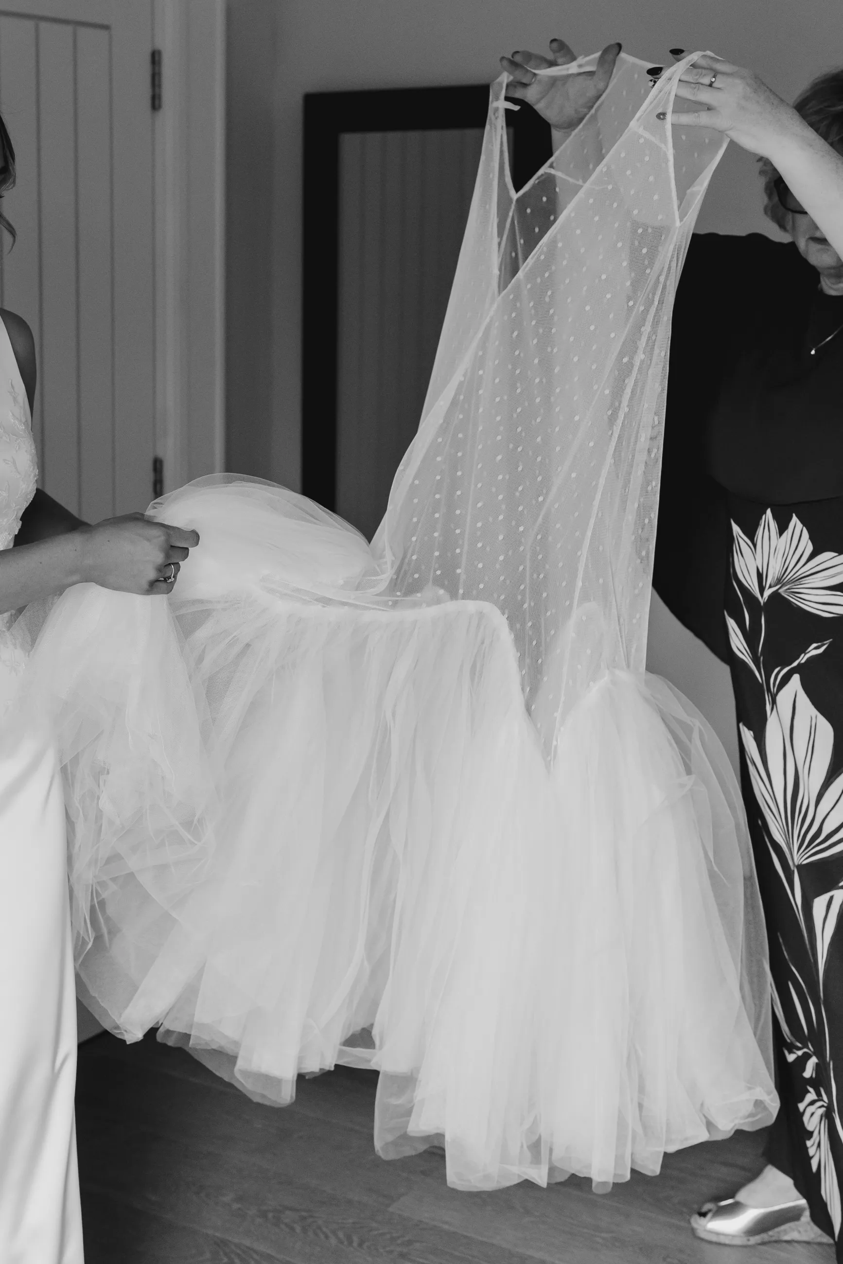 The wave hem spot tulle overdress being lifted over Tasha’s gown on the morning of her wedding