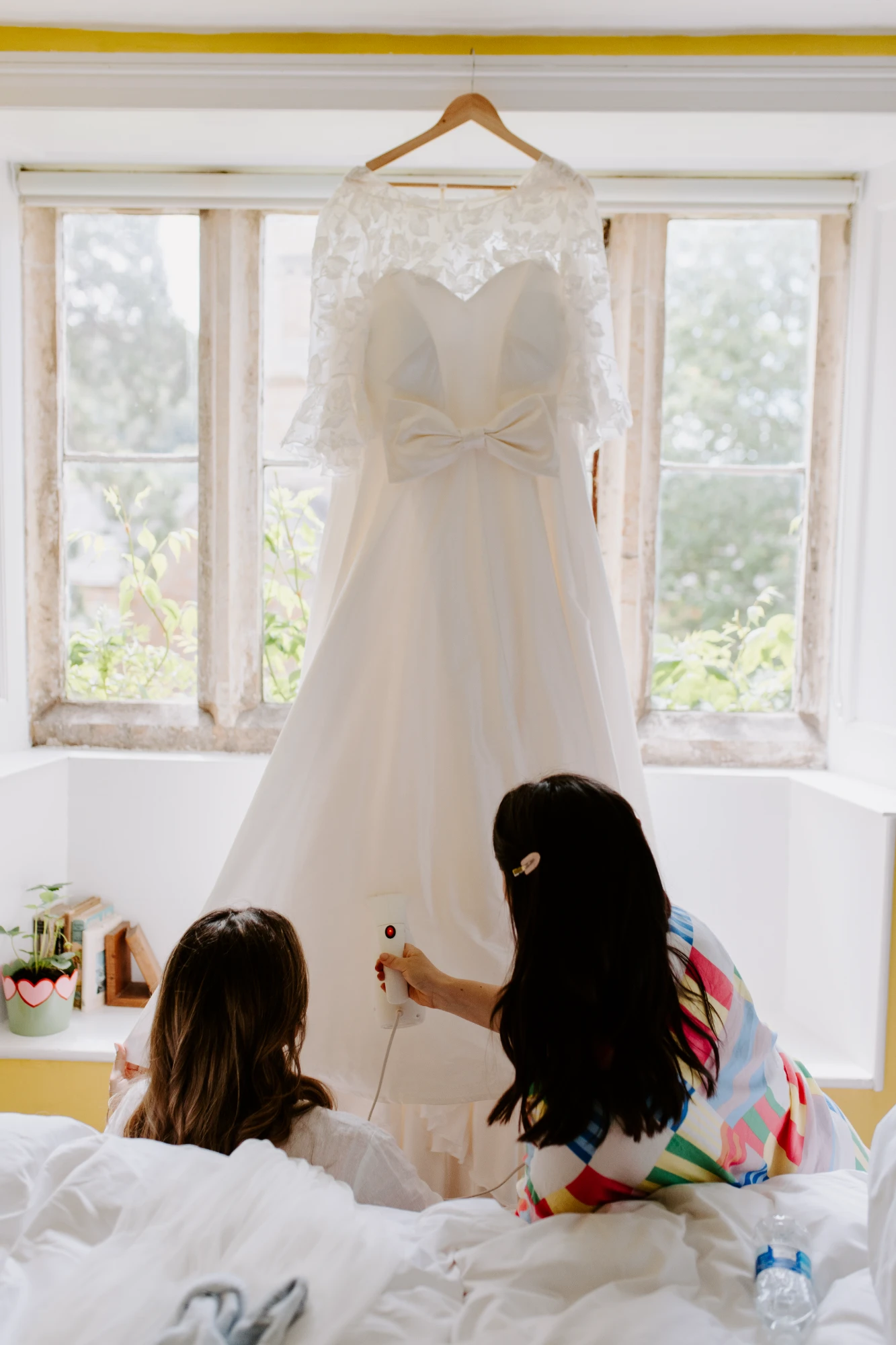 Custom ivory beaded lace wedding dress with a silk taffeta skirt, featuring a bow from the bride's mother's dress