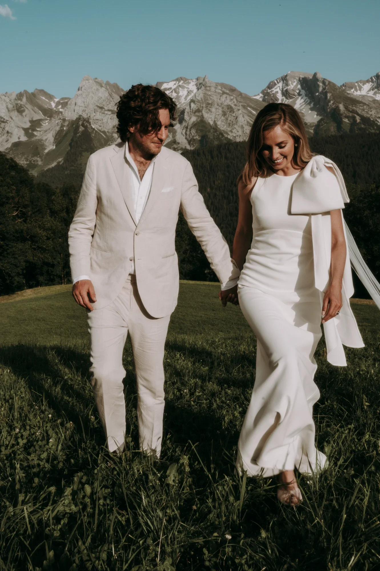 Custom crepe wedding dress with an oversized bow detail and detachable tulle train, made for a French Alps wedding