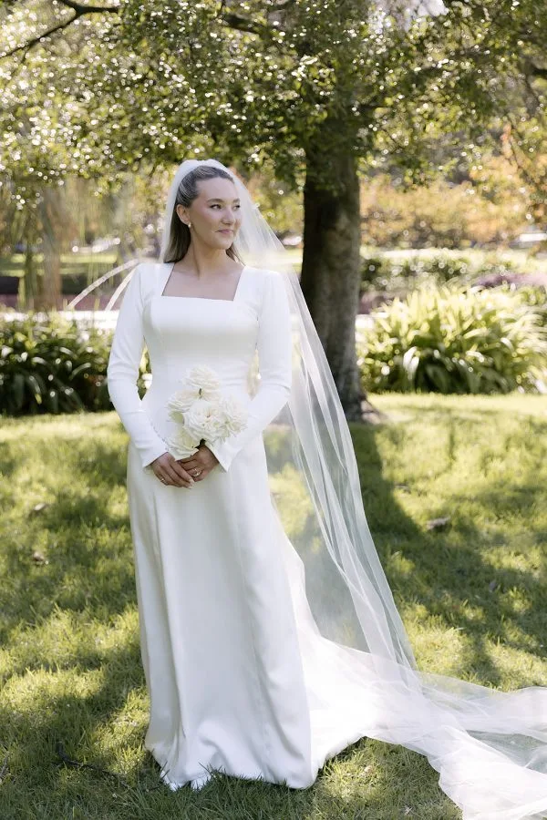 Custom satin wedding dress with a square neckline, dropped-waist corset and full-length sleeves
