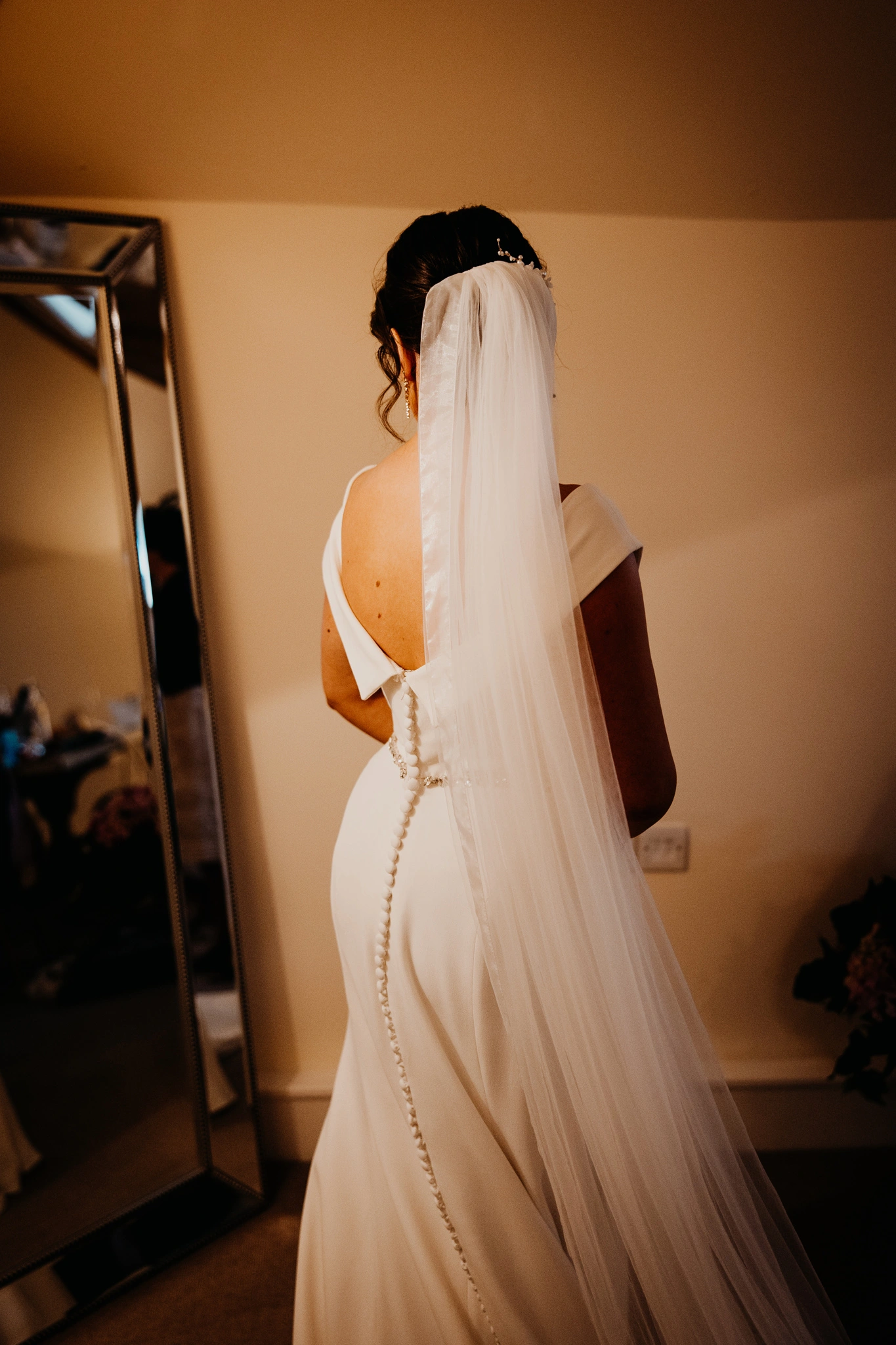 Custom ivory crepe fit-and-flare wedding dress, back view showing the bustle and covered buttons